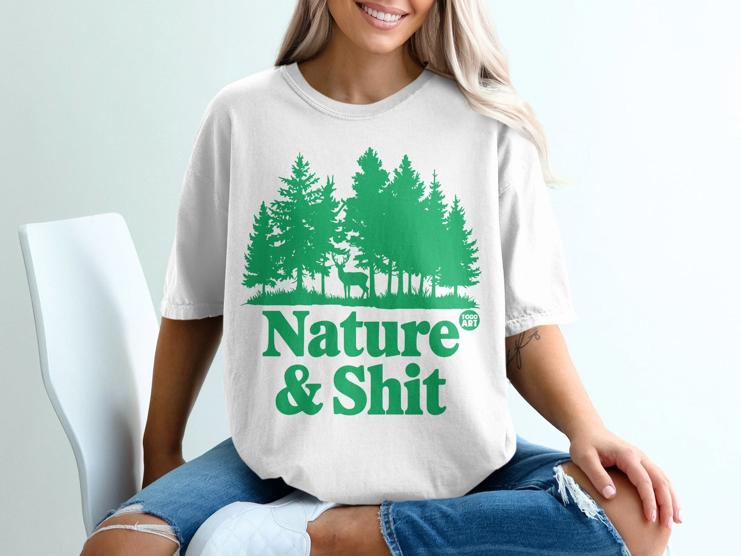 White t-shirt with green forest and deer graphic, text "Nature & Shit".