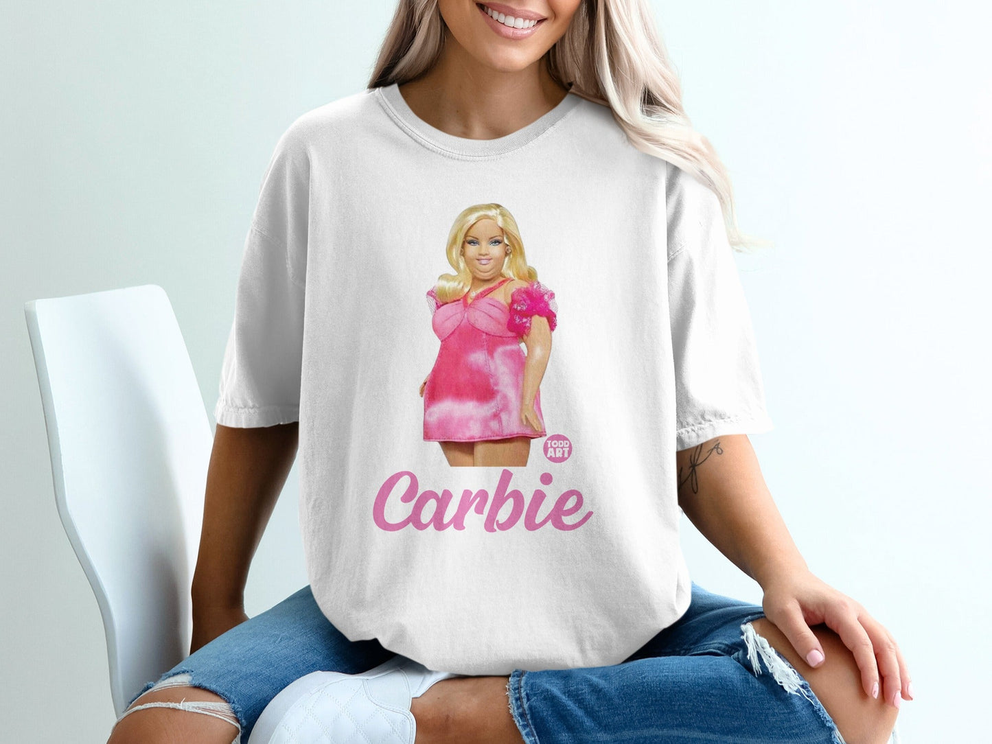 White t-shirt with "Carbie" text and cartoon drawing of a woman in a pink dress.