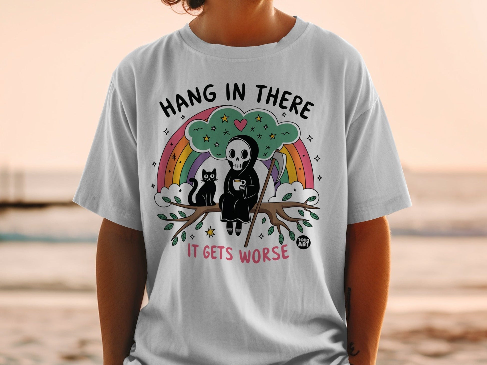 White t-shirt with Grim Reaper and cat on a branch, rainbow, and text.