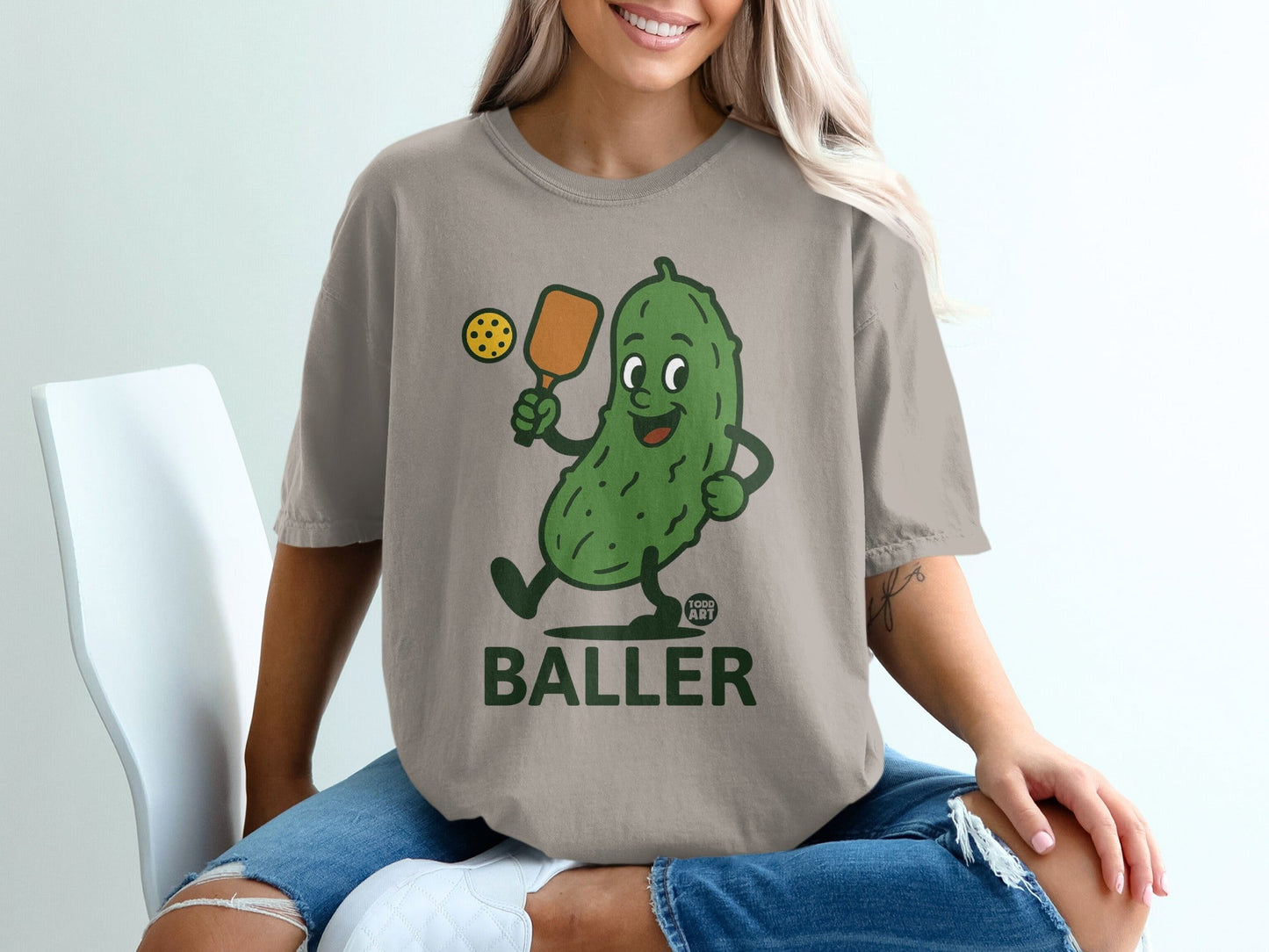 Cartoon pickle holding a paddle and ball, with "BALLER" text.
