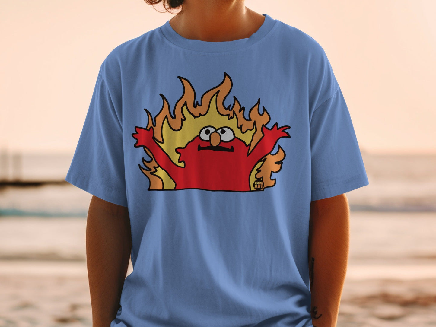 T-shirt featuring Elmo engulfed in cartoon flames, with "GOOD ART" logo.