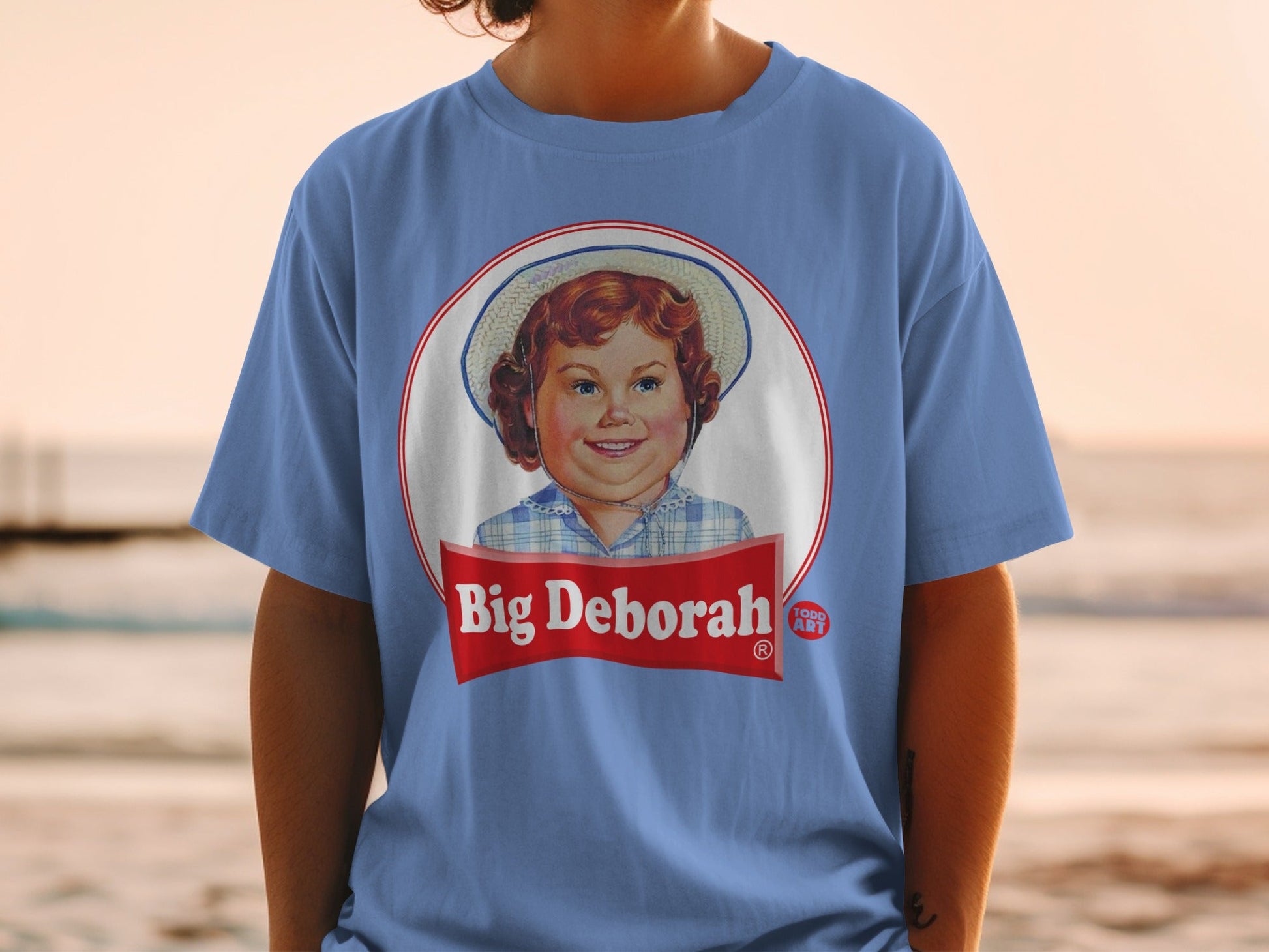 Blue t-shirt with "Big Deborah" label featuring a smiling girl in a straw hat.