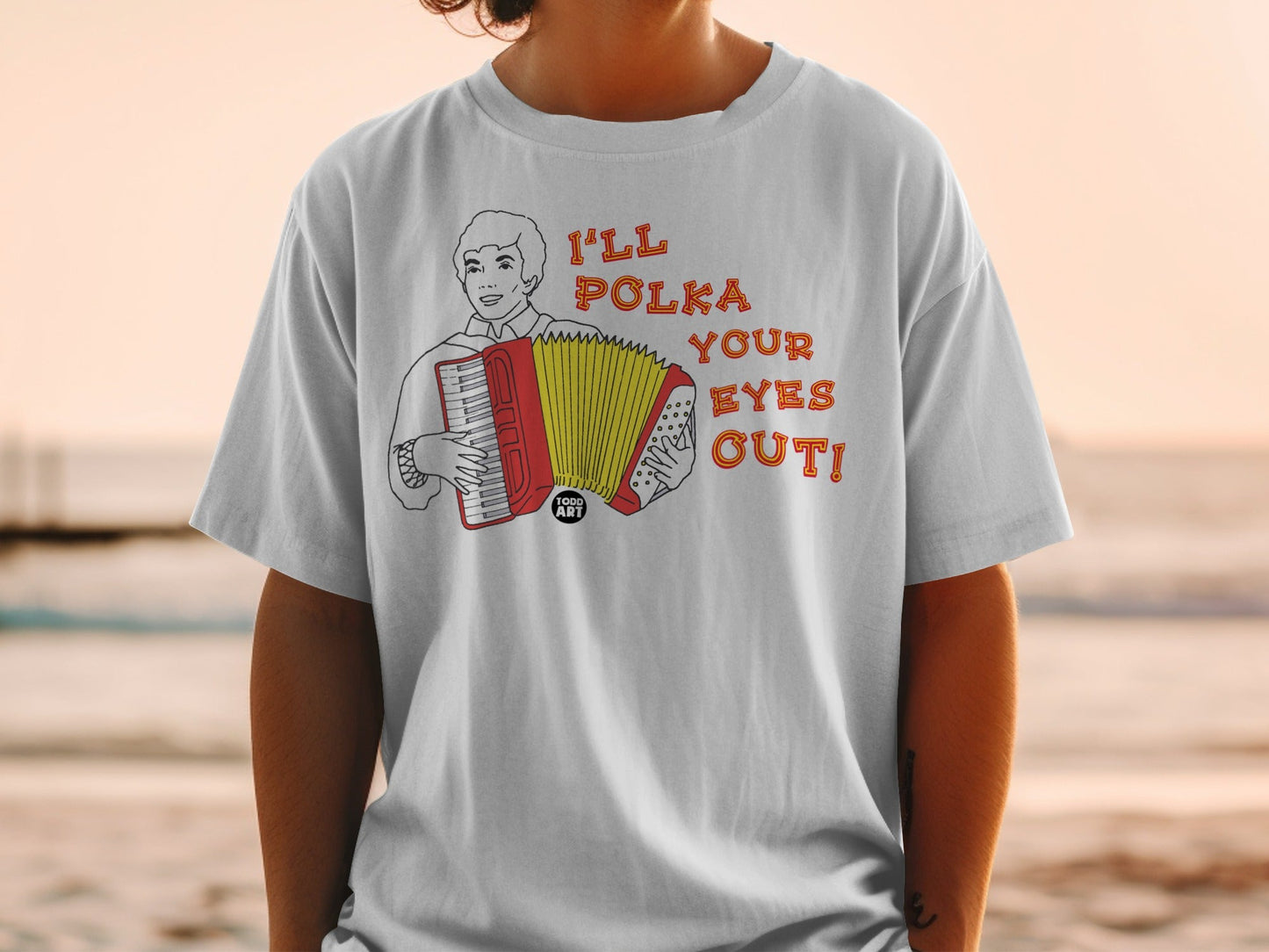 White t-shirt with graphic of a man playing accordion and text "I'LL POLKA YOUR EYES OUT!".