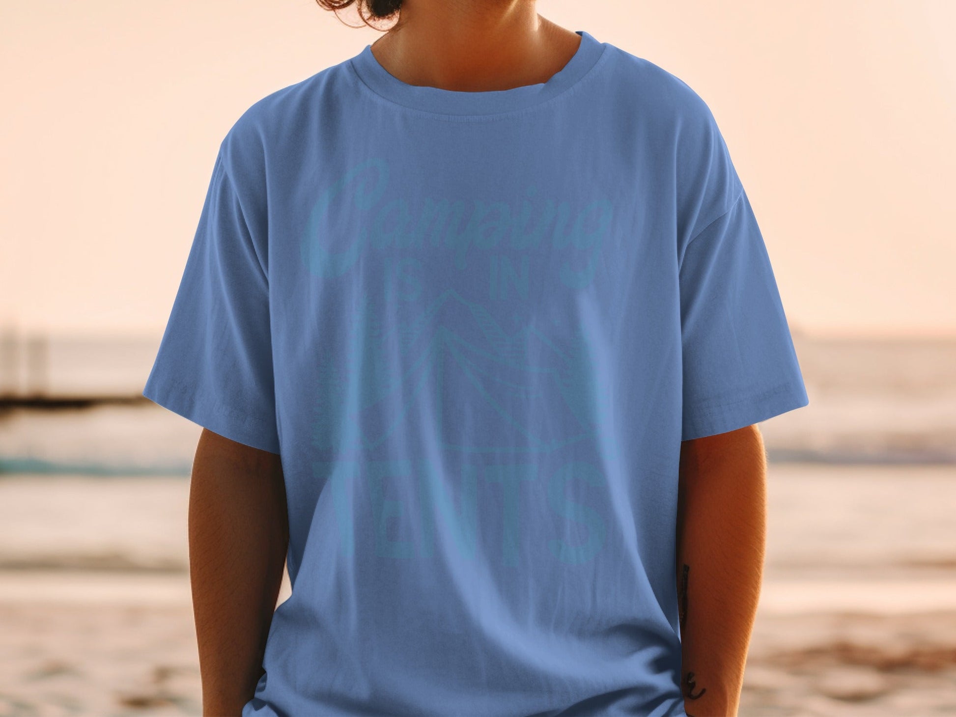 Blue t-shirt with "Camping is in my DNA" text and mountain graphic.