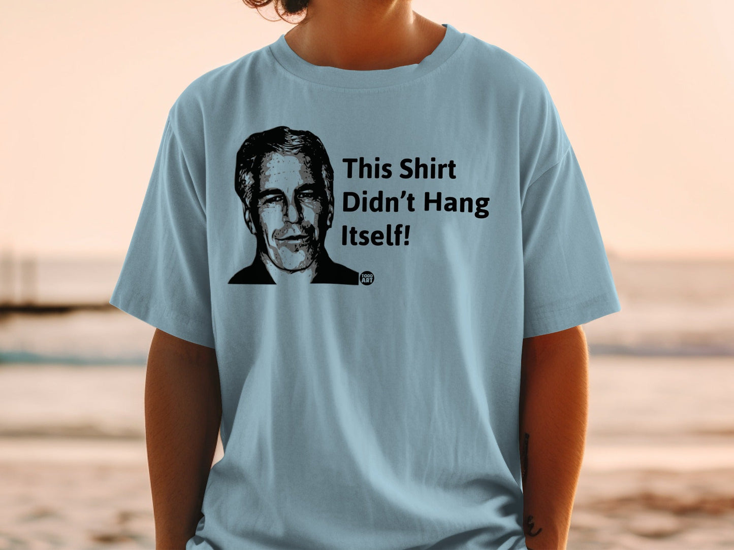 Light blue t-shirt with portrait and "This Shirt Didn't Hang Itself!" text.