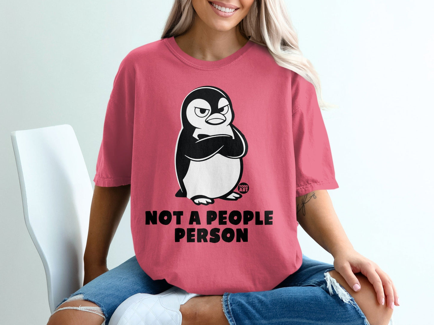 Pink t-shirt with a grumpy penguin and text "NOT A PEOPLE PERSON".
