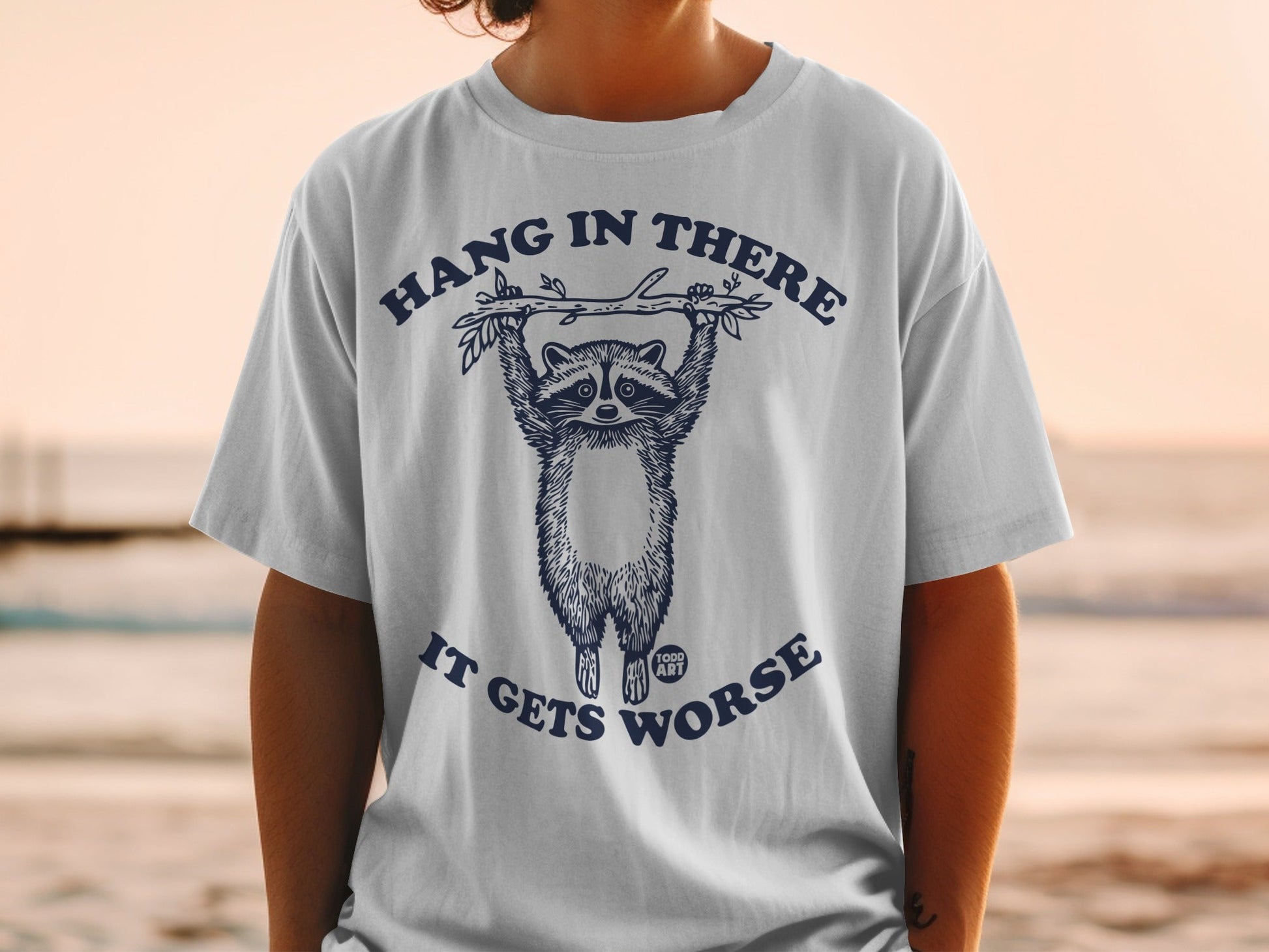 Raccoon hanging from branch with text "Hang in there, it gets worse."