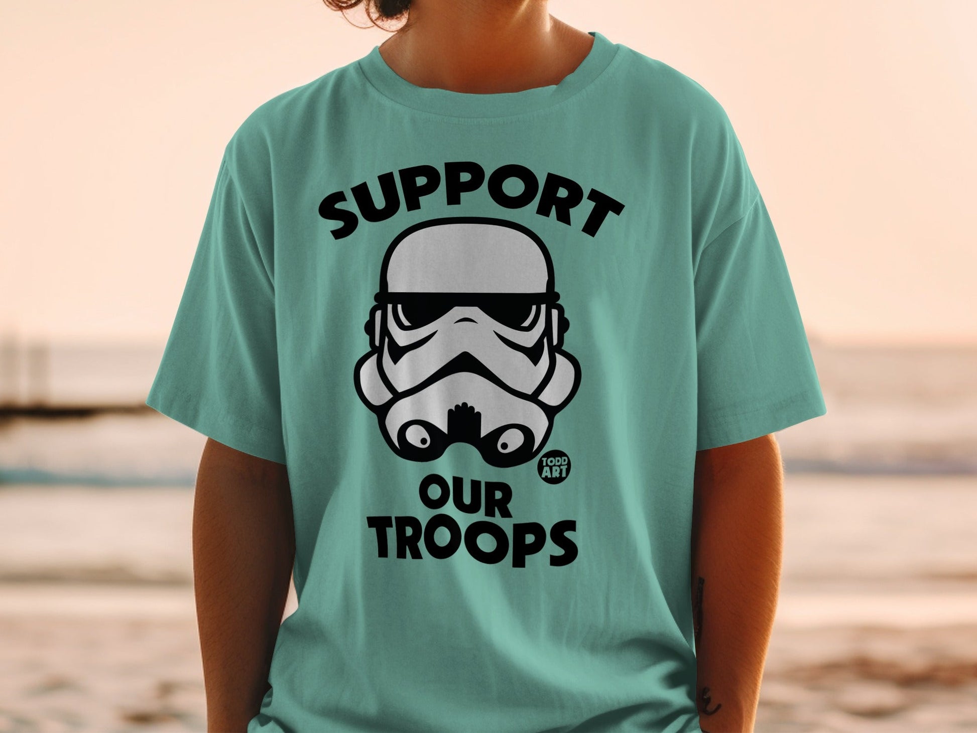Teal t-shirt with black Star Wars Stormtrooper helmet graphic and "SUPPORT OUR TROOPS" text.