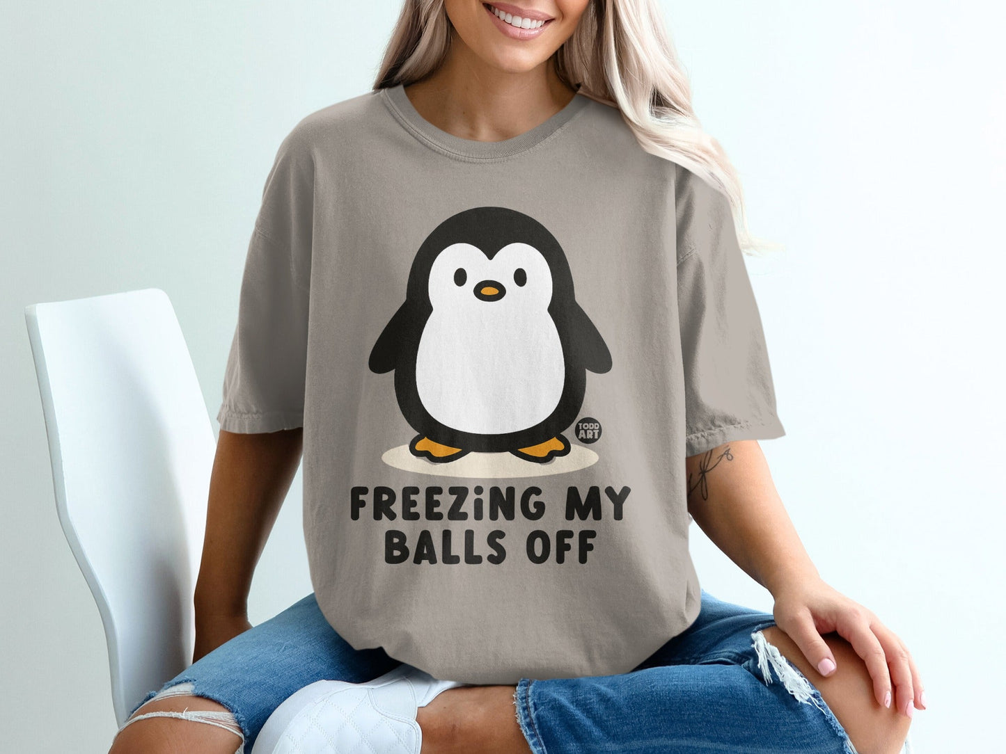 Graphic t-shirt with a cartoon penguin and text "FREEZING MY BALLS OFF".