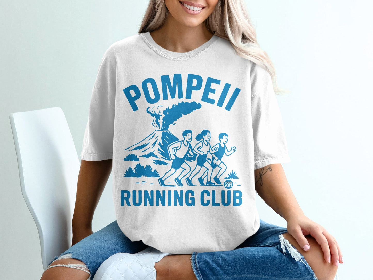 White t-shirt with "Pompeii Running Club" text and graphic of runners with volcano.