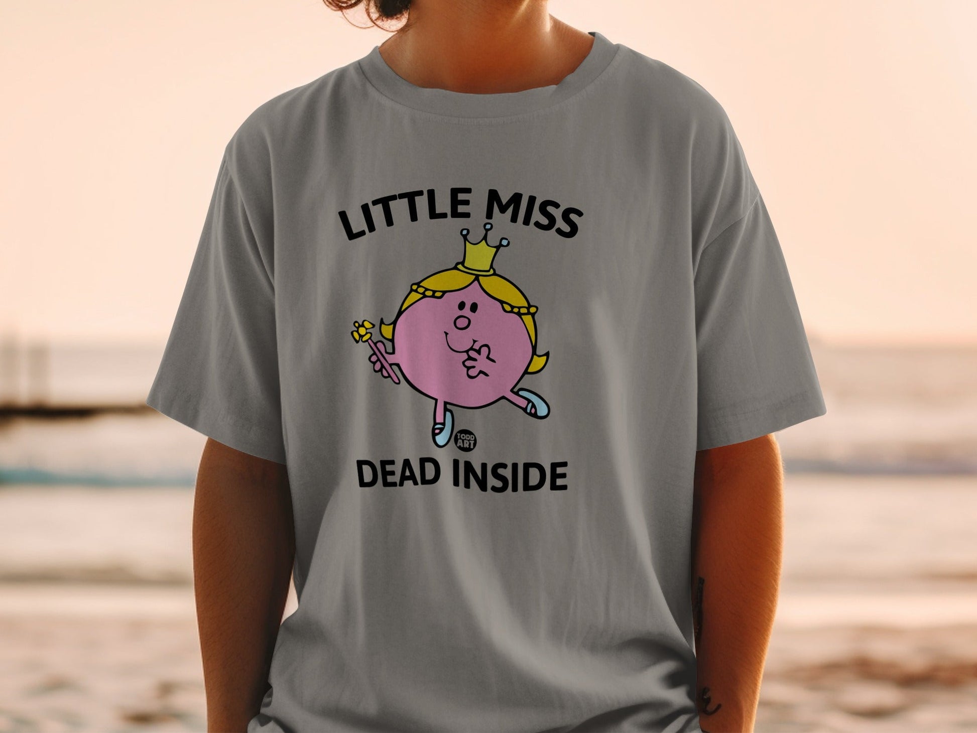 Little Miss Dead Inside graphic tee on a person, beach background