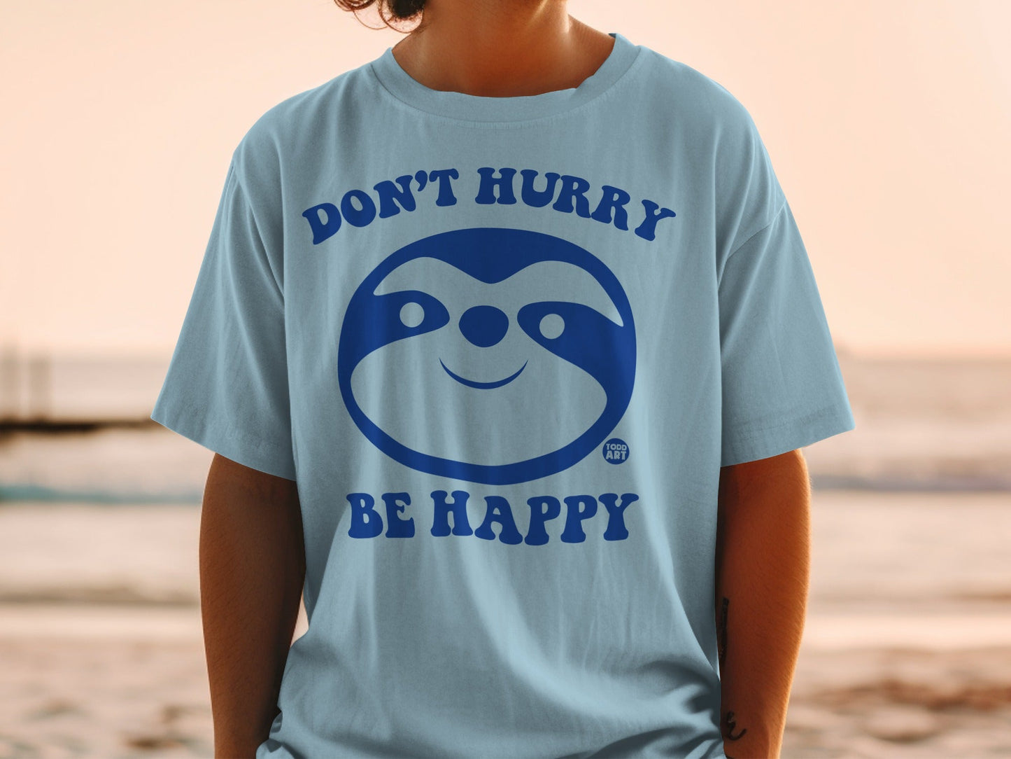 Light blue t-shirt with "DON'T HURRY BE HAPPY" and a smiling sloth graphic.