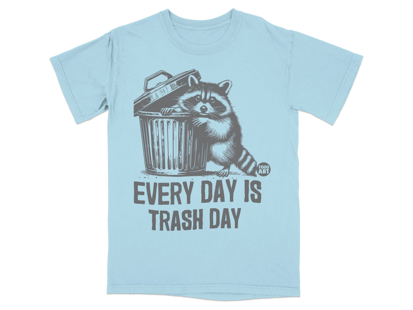 Light blue t-shirt with a raccoon peeking out of a trash can, text reads "EVERY DAY IS TRASH DAY".