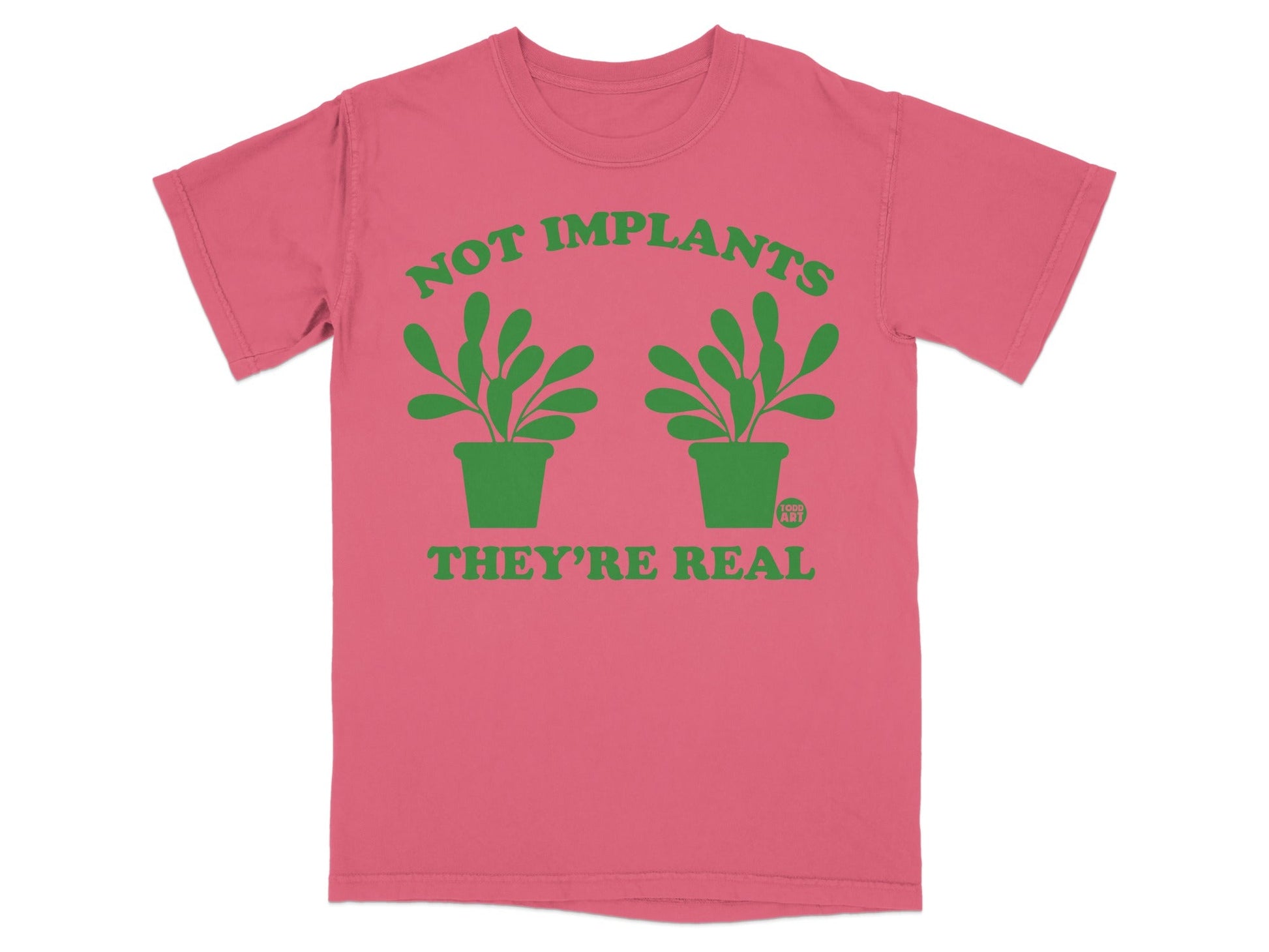 Pink t-shirt with green text "NOT IMPLANTS THEY'RE REAL" and two potted plants.