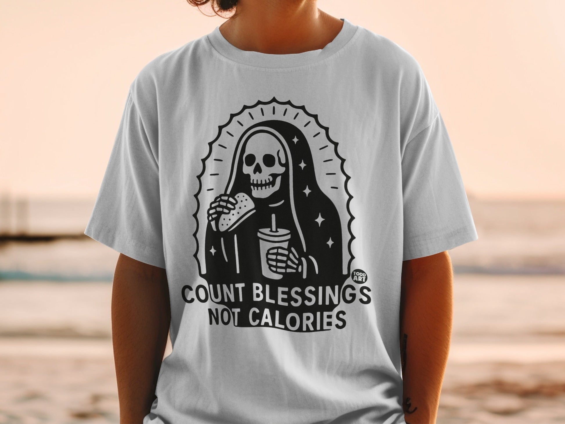 T-shirt with Grim Reaper eating fast food, "COUNT BLESSINGS NOT CALORIES" text.