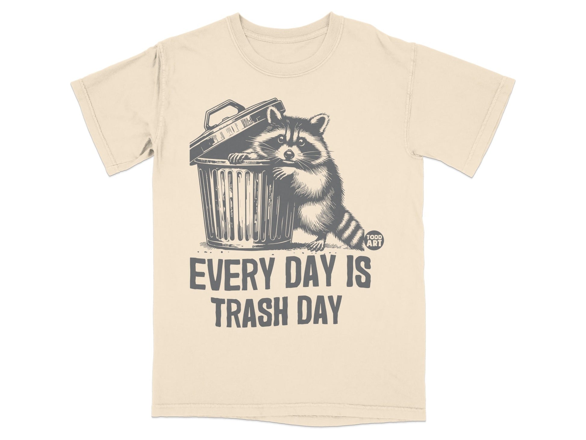 Cream t-shirt with raccoon peeking from trash can, "EVERY DAY IS TRASH DAY" text.
