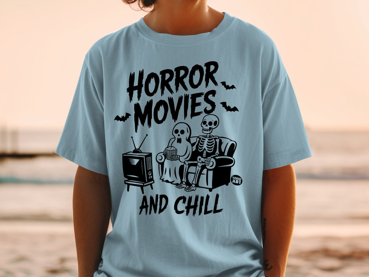 Light blue t-shirt with "Horror Movies and Chill" text and skeleton couple watching TV.