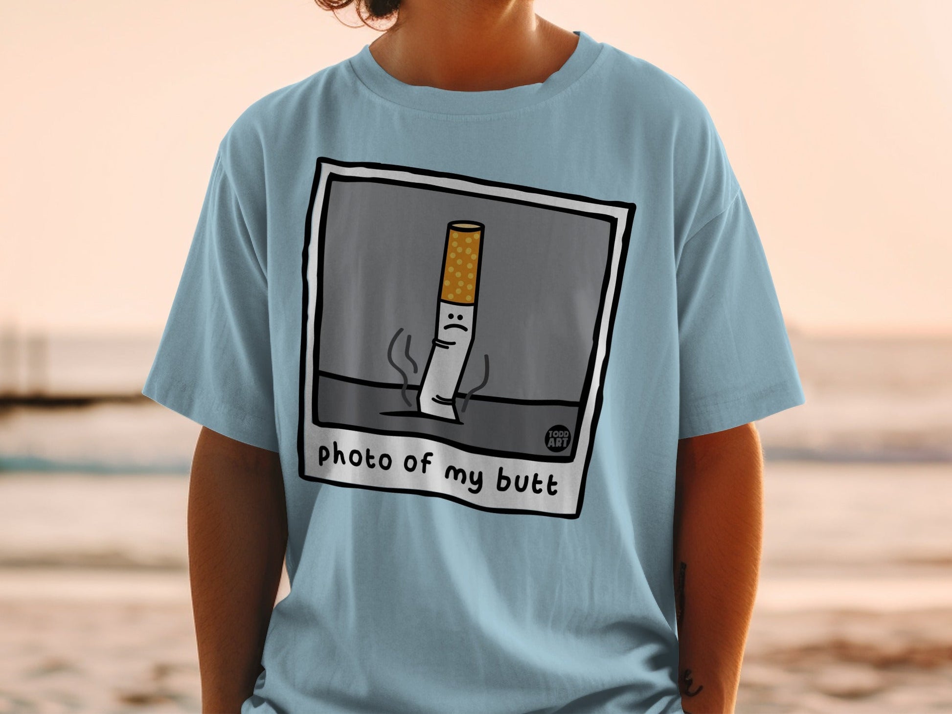 Light blue t-shirt with cartoon cigarette saying "photo of my butt".