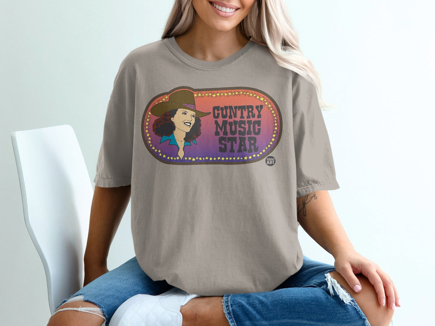 Graphic t-shirt with oval logo featuring woman and "GUNTry MUSIC STAR" text.