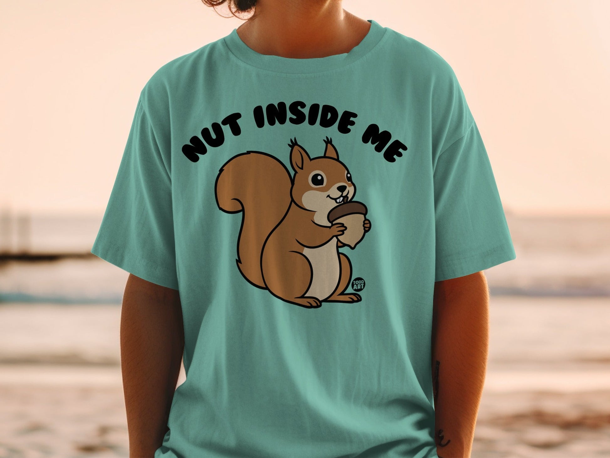 Teal t-shirt with a cartoon squirrel holding an acorn and the text "NUT INSIDE ME".