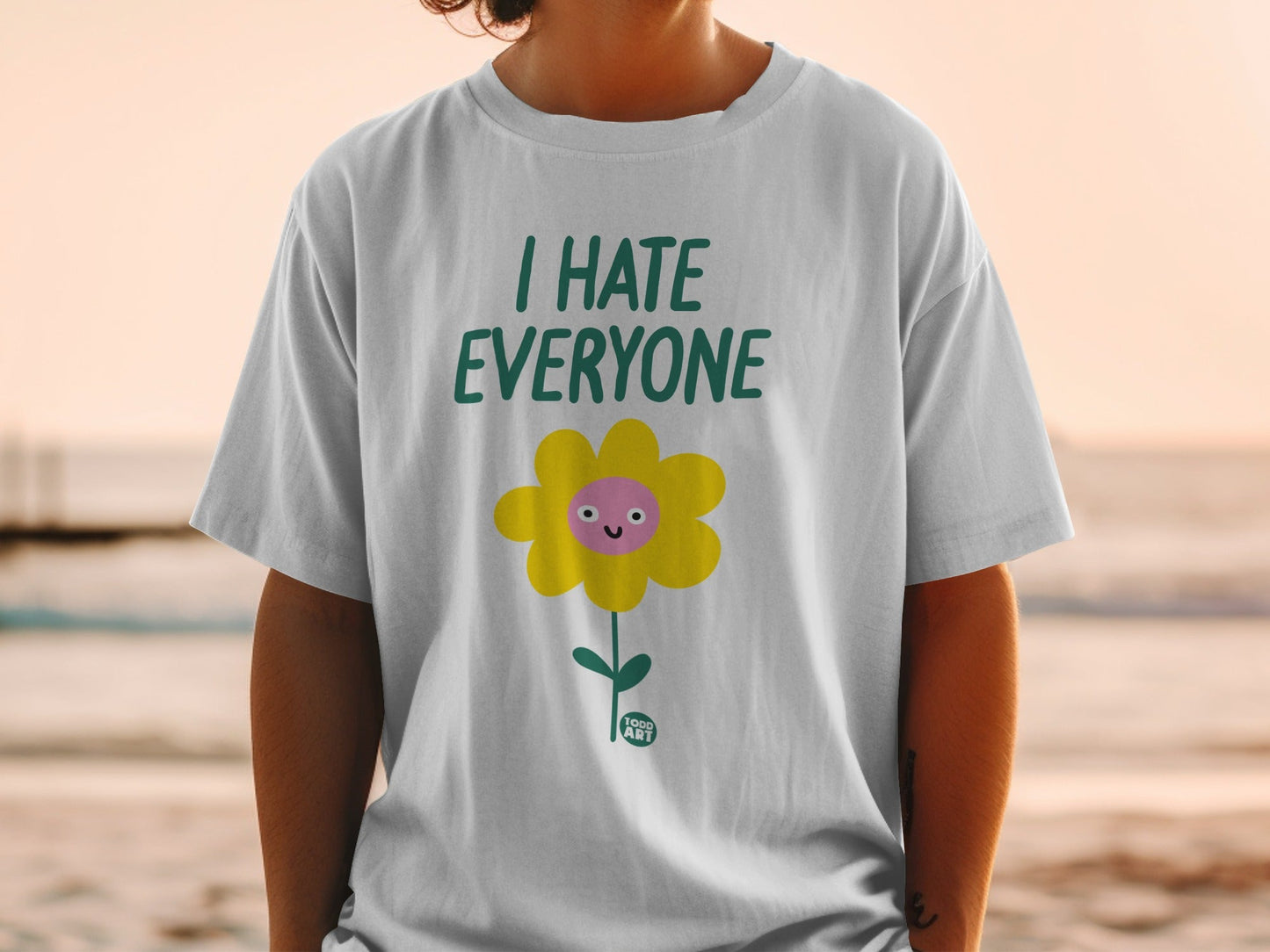 White t-shirt with a yellow flower graphic that says "I HATE EVERYONE".