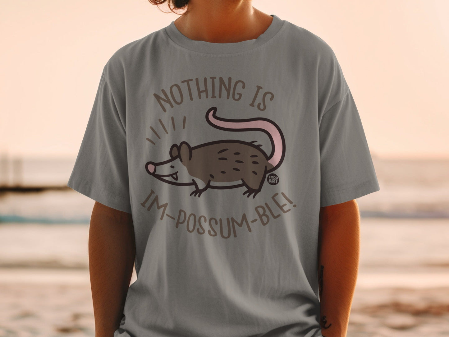 Gray t-shirt with cartoon opossum and "Nothing is im-possum-ble!" text.
