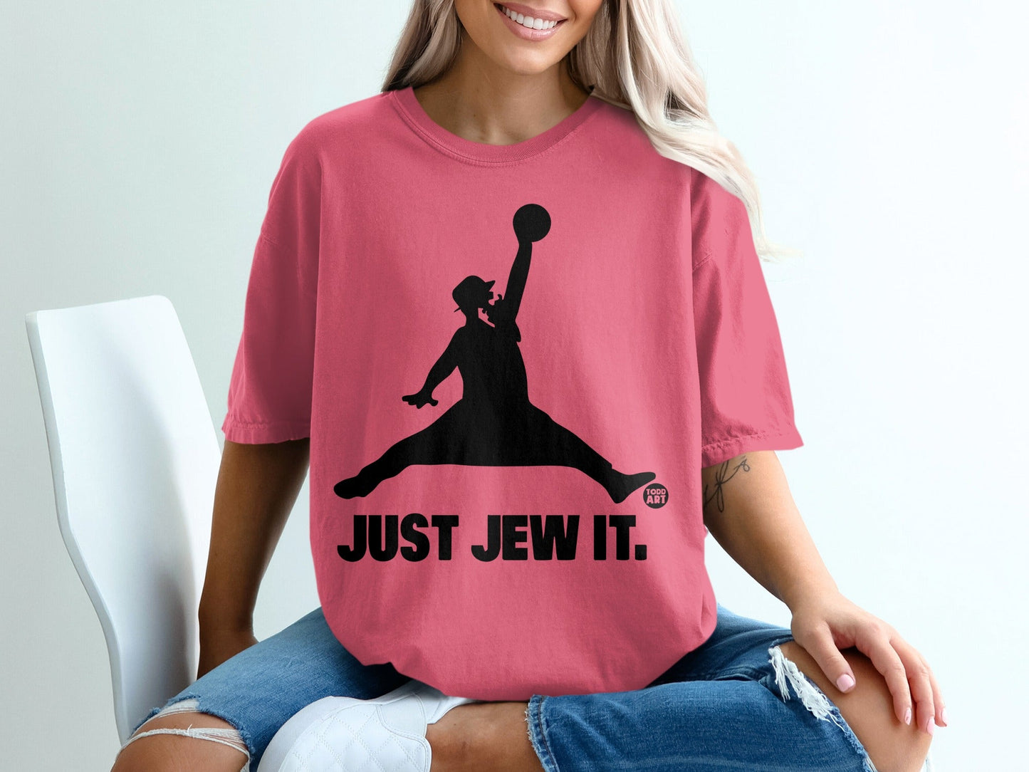 Pink t-shirt with silhouette of a person jumping to dunk a basketball, "JUST JEW IT." text.