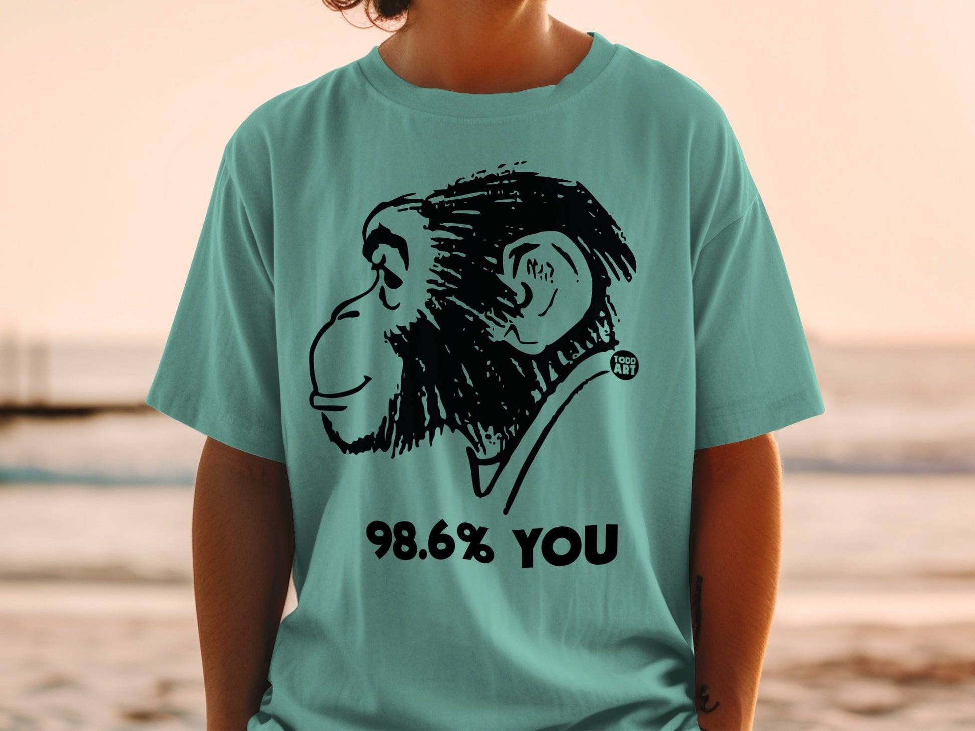 Teal t-shirt with a black line drawing of a chimpanzee and text "98.6% YOU".