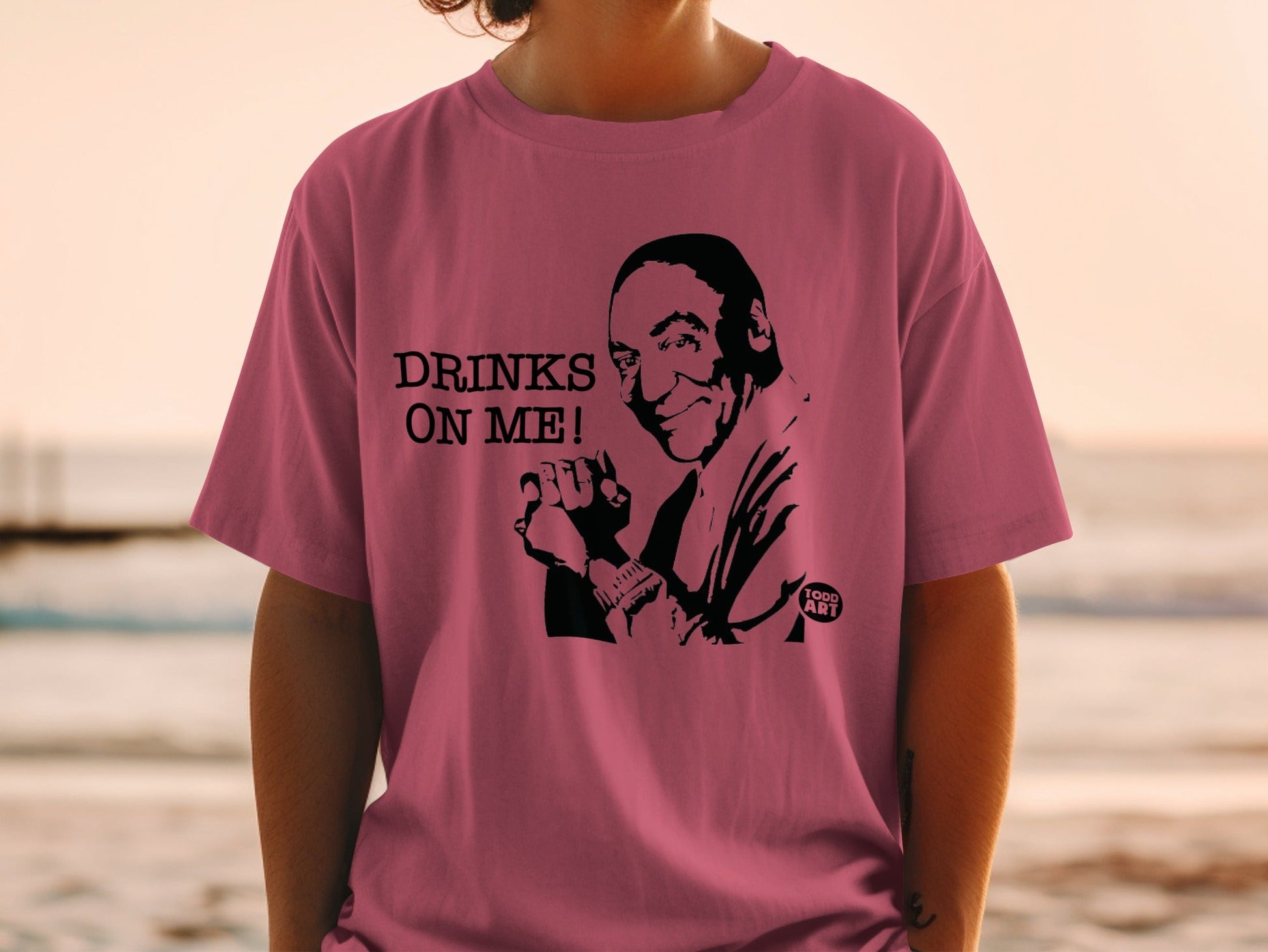 T-shirt with a graphic of a man's face and "DRINKS ON ME!" text.