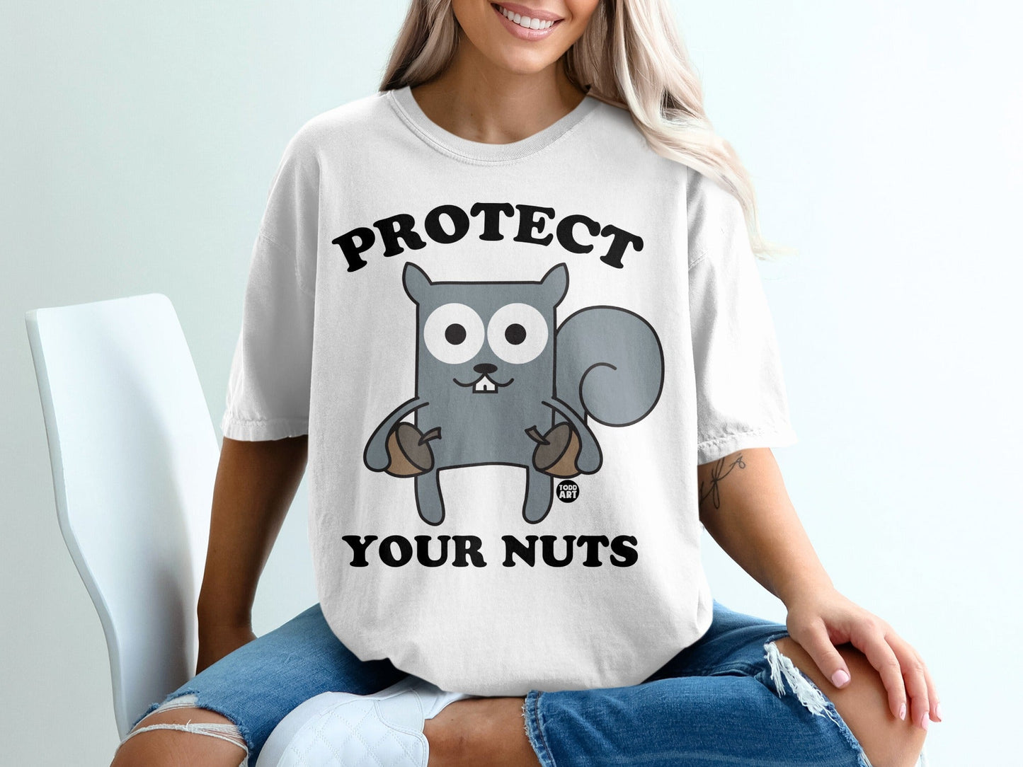 T-shirt with cartoon squirrel holding acorns and text "PROTECT YOUR NUTS".