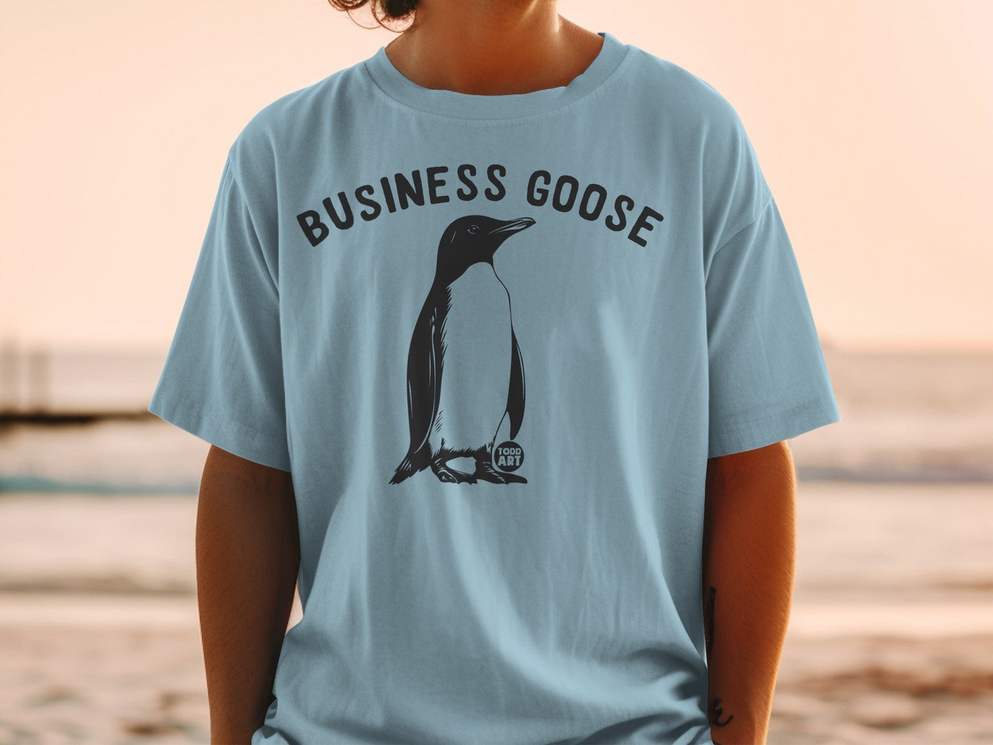 Light blue t-shirt with a penguin illustration and "BUSINESS GOOSE" text.