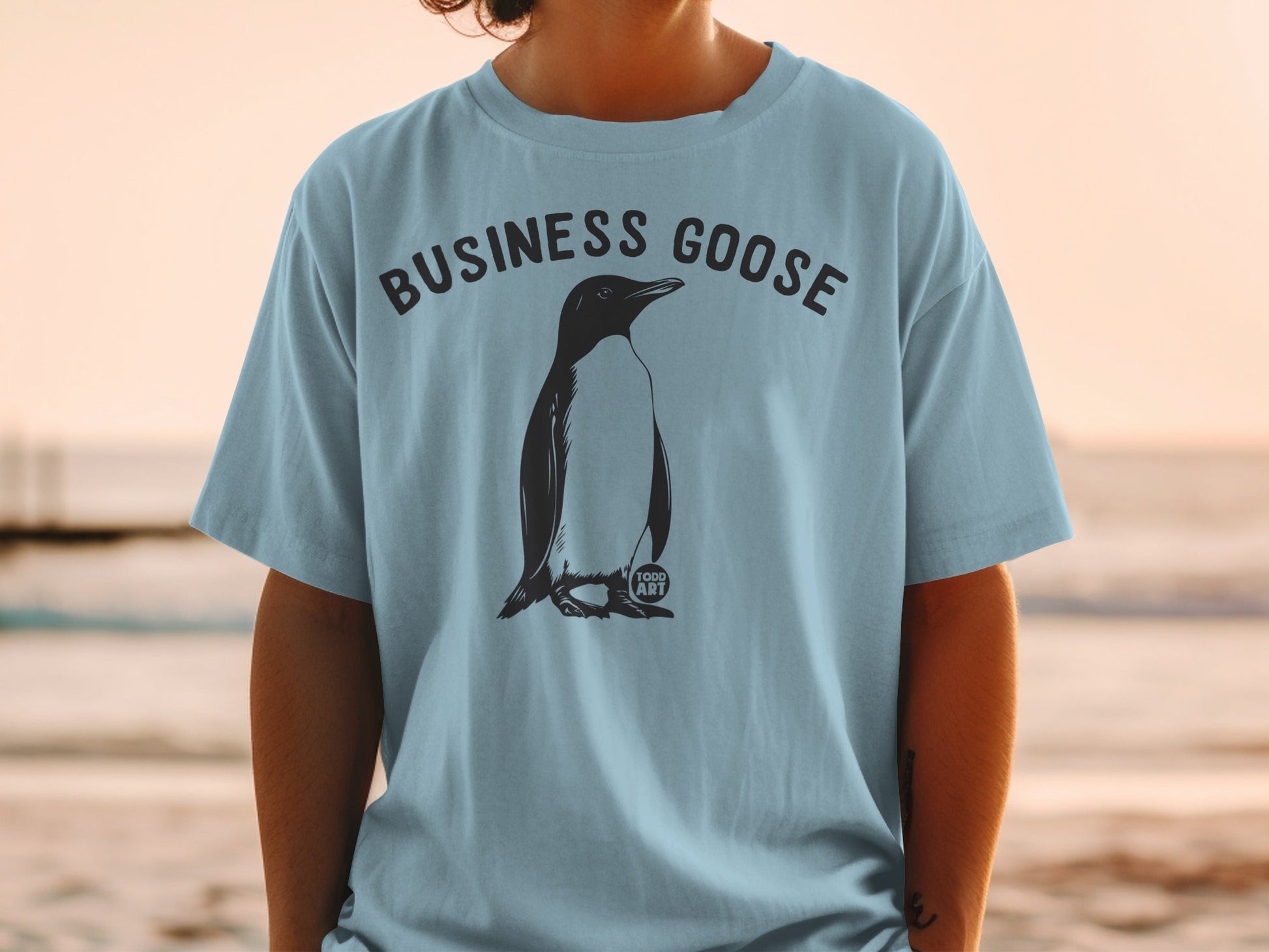 Light blue t-shirt with a penguin illustration and "BUSINESS GOOSE" text.