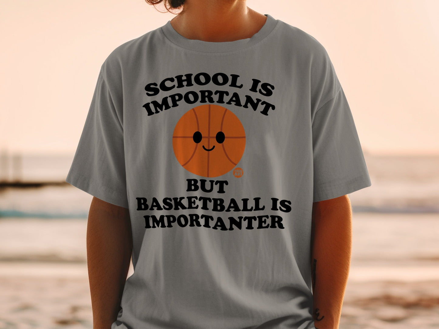 Gray t-shirt with text "School is important but basketball is importanter" and a cartoon basketball.