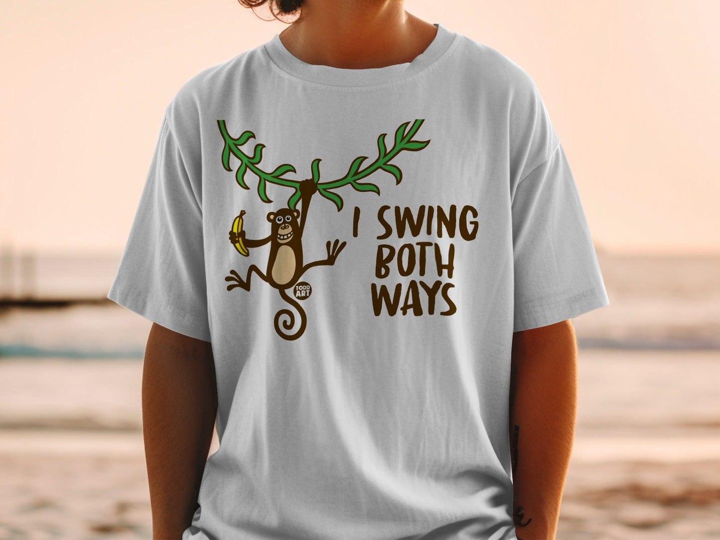 T-shirt with monkey swinging from a vine holding a banana and text "I SWING BOTH WAYS".