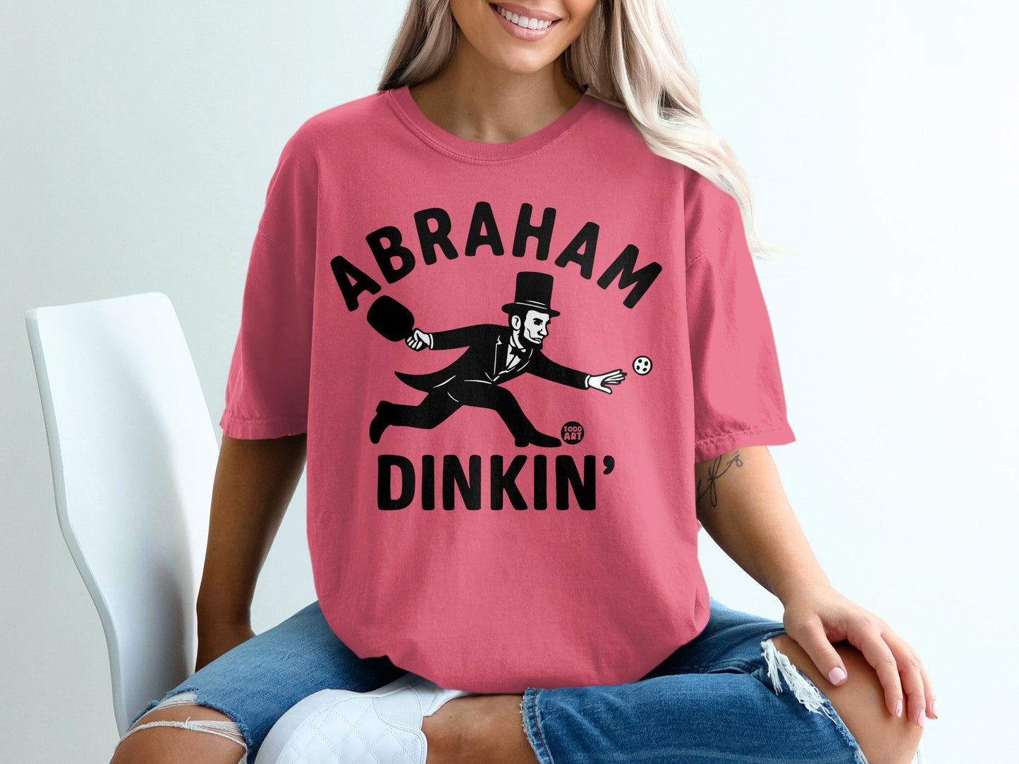 Abraham Lincoln in a top hat playing croquet on a pink t-shirt.