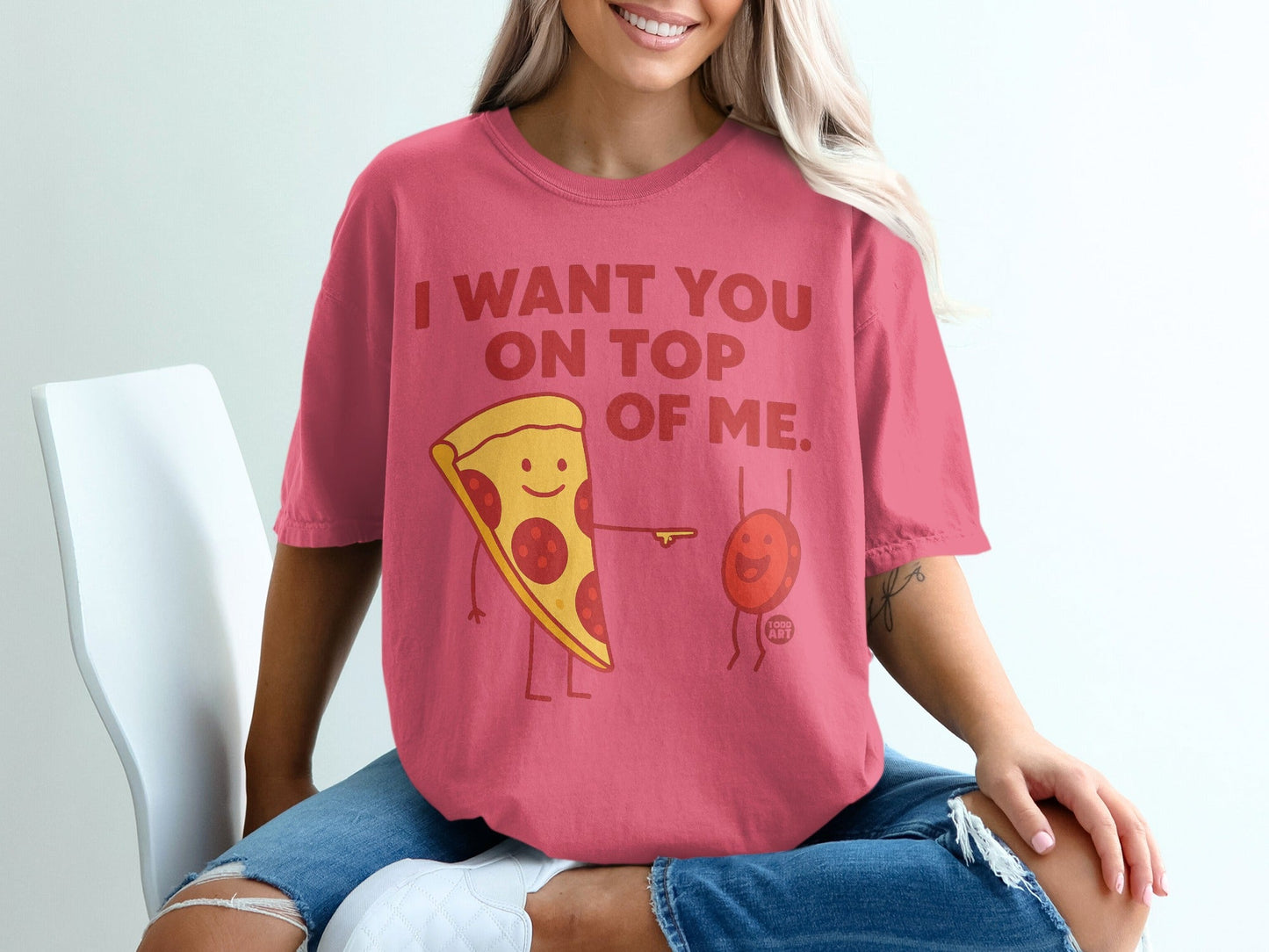 Pink t-shirt with cartoon pizza and red dot saying "I want you on top of me."