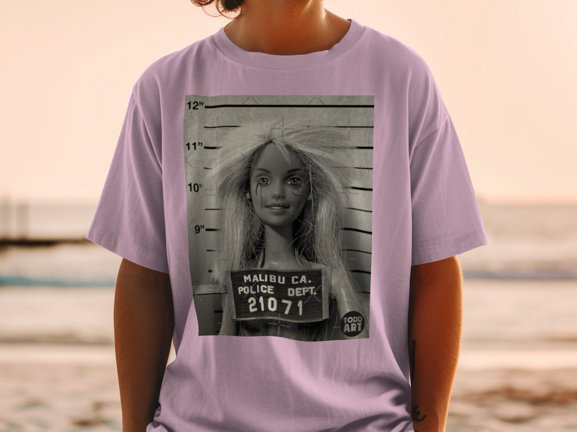Pink t-shirt with a mugshot of a doll with "Malibu CA Police Dept. 21071 Todd Art" text.