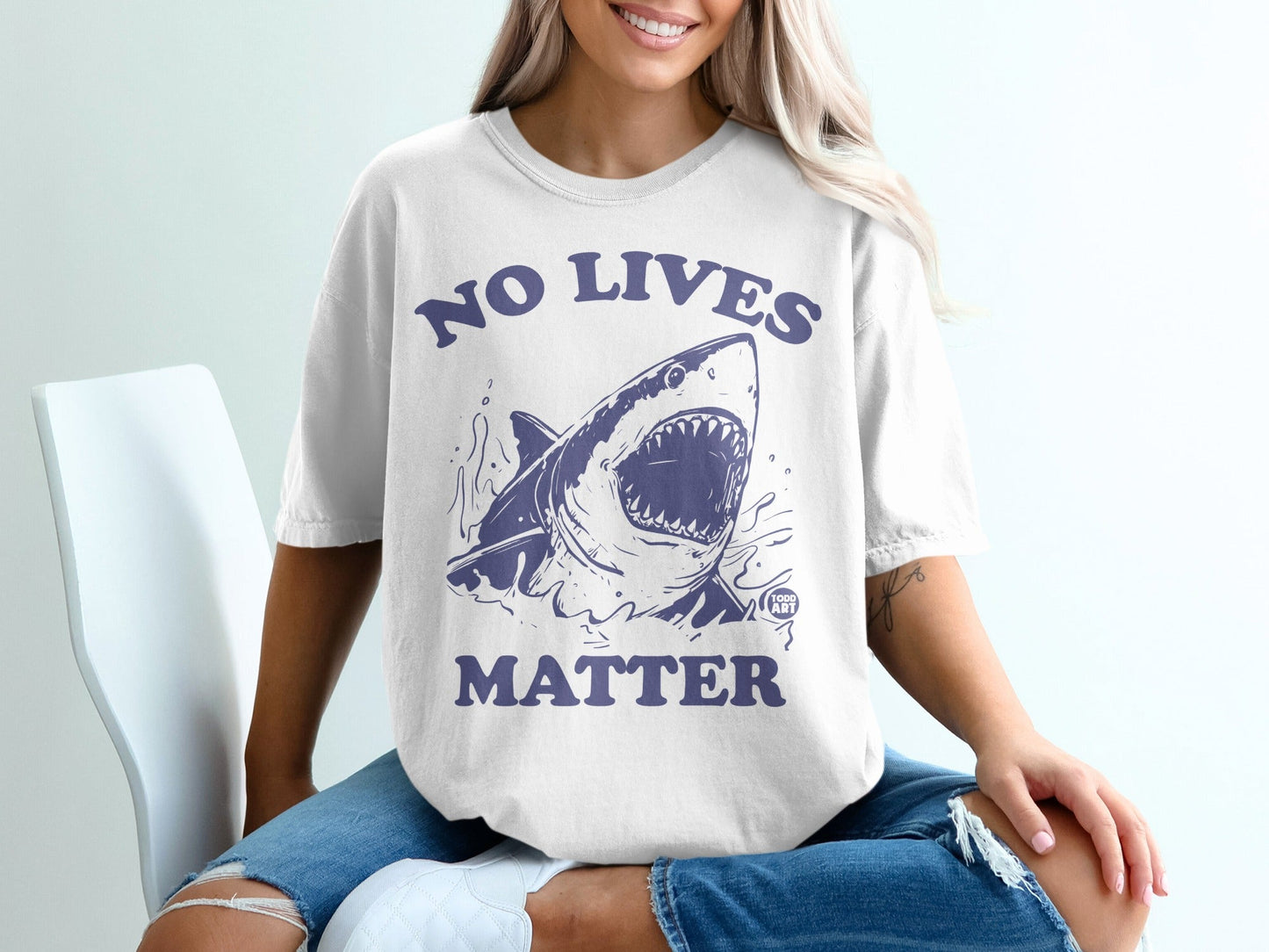 White t-shirt with dark blue graphic of a shark and text "NO LIVES MATTER".