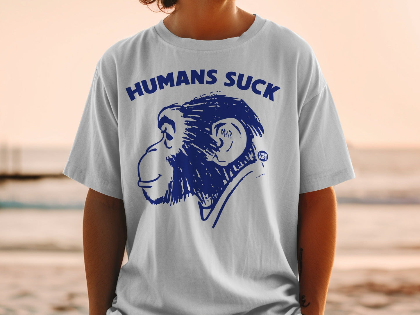 White t-shirt with blue cartoon monkey and text "HUMANS SUCK".