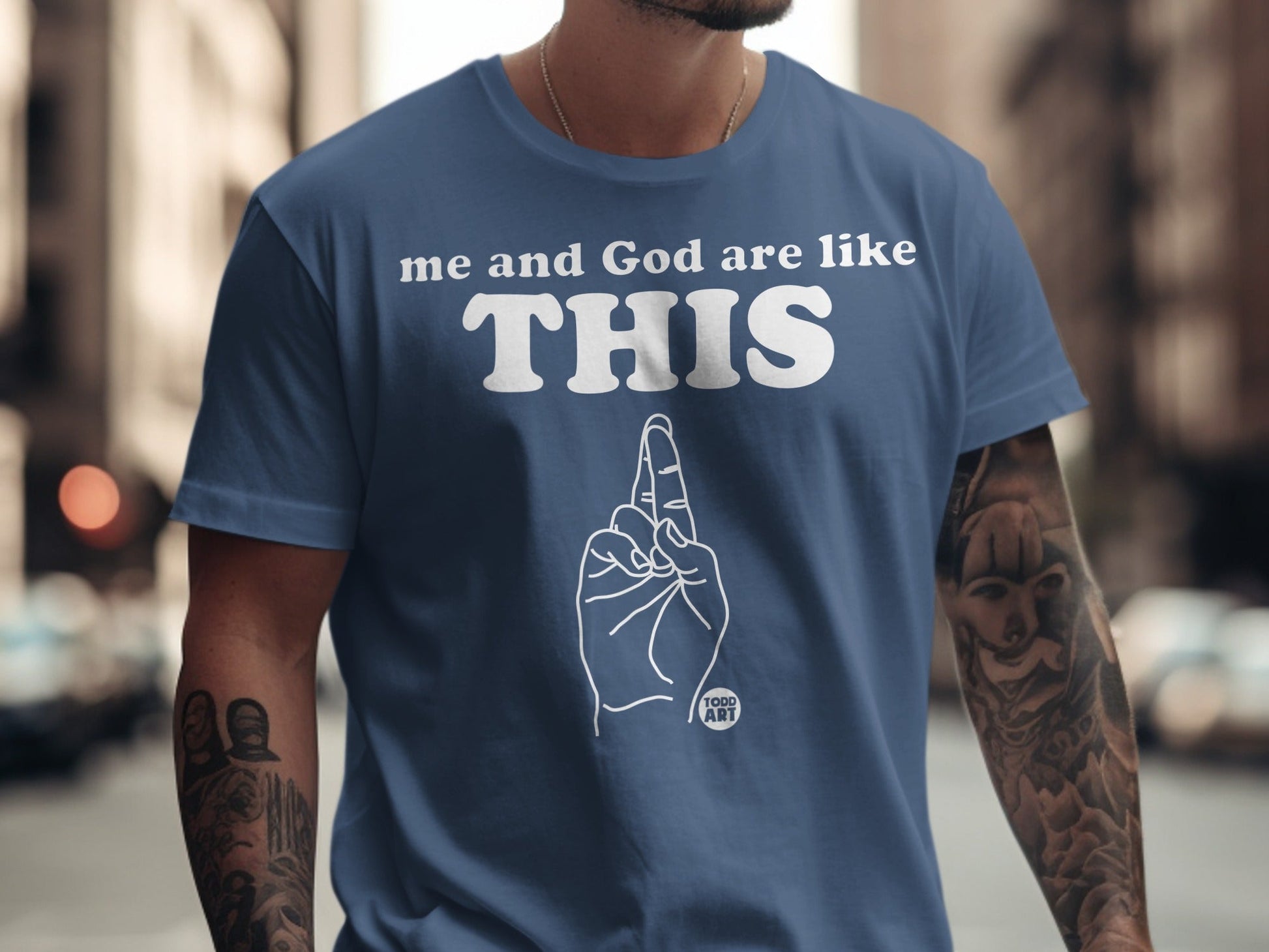 Blue t-shirt with white text "me and God are like THIS" and a hand gesture.