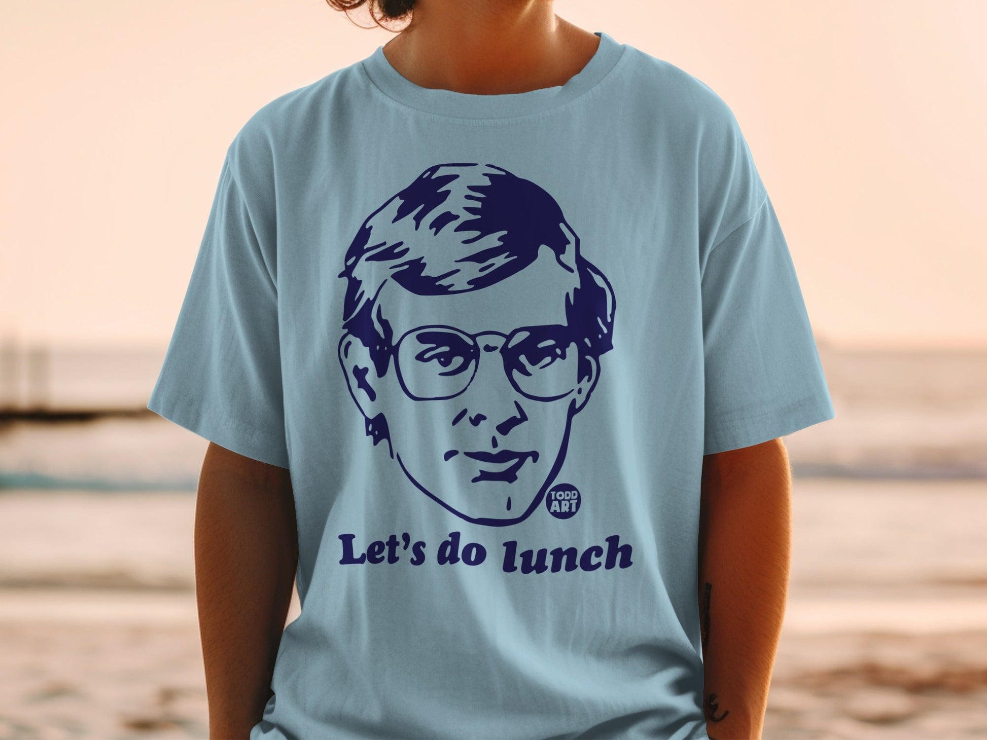 Light blue t-shirt with a graphic of a person's face and "Let's do lunch".