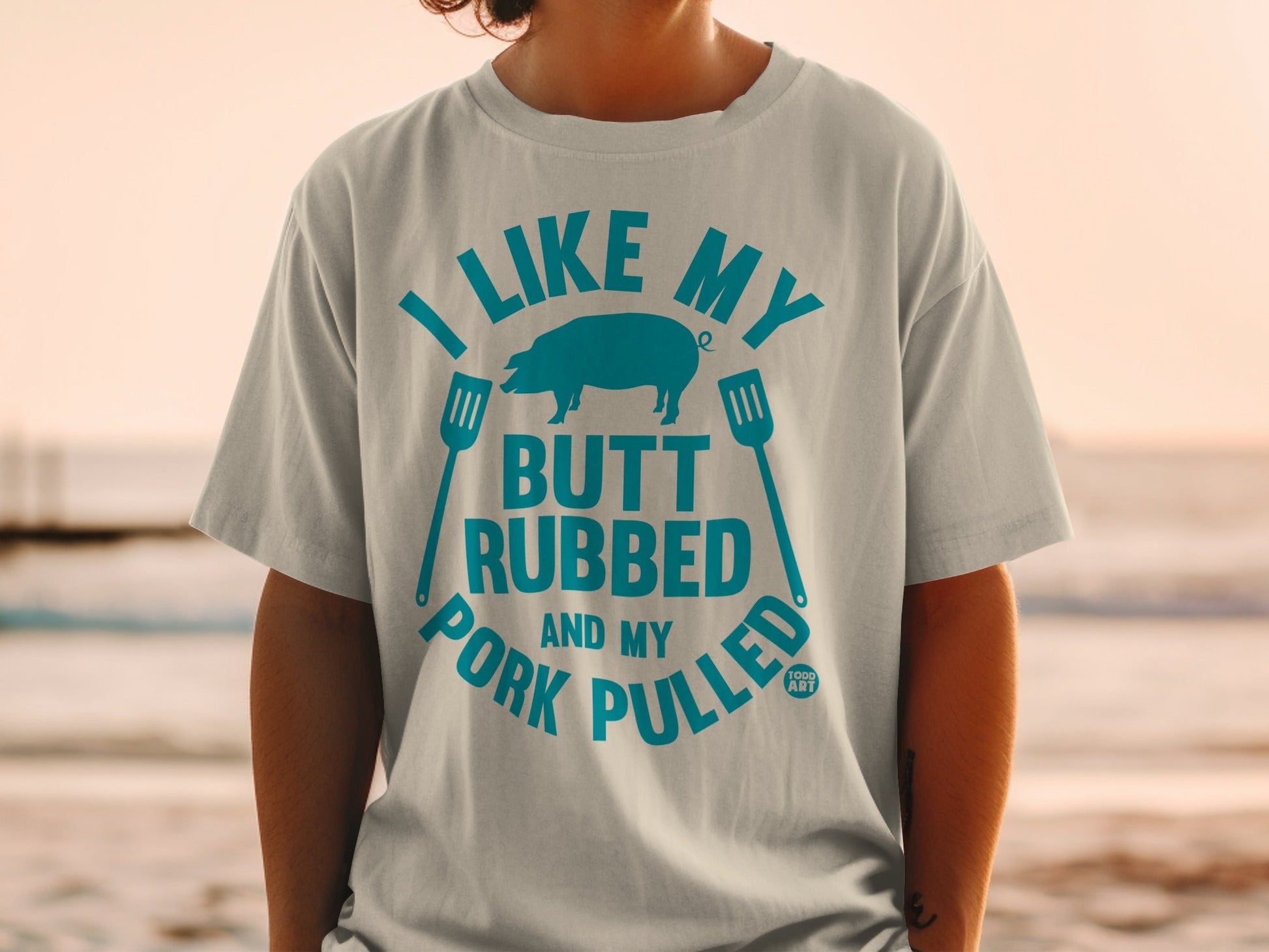 T-shirt with blue text "I LIKE MY BUTT RUBBED AND MY PORK PULLED" and a pig graphic.