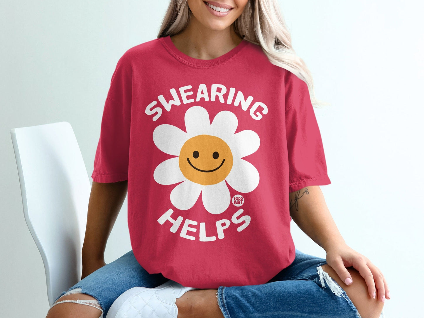 Red t-shirt with a smiling flower graphic and text "SWEARING HELPS".