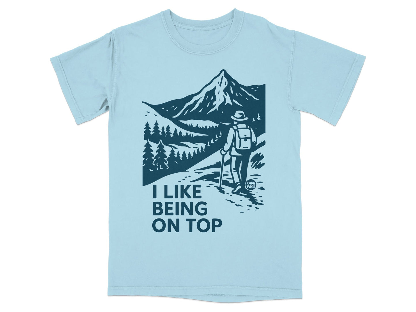 Light blue t-shirt with a mountain hiking graphic and text "I LIKE BEING ON TOP".