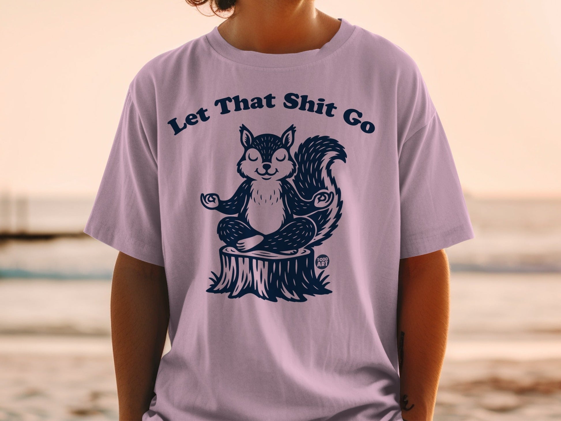 T-shirt with a meditating squirrel on a tree stump, text "Let That Shit Go."