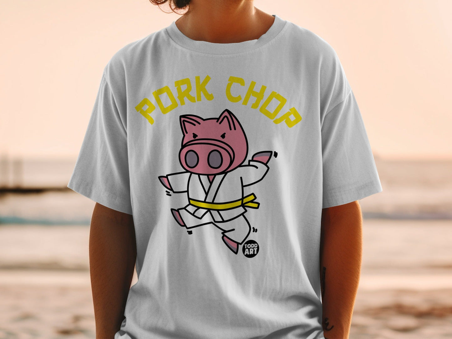 White t-shirt with yellow text "Pork Chop" and cartoon pig in karate gi.