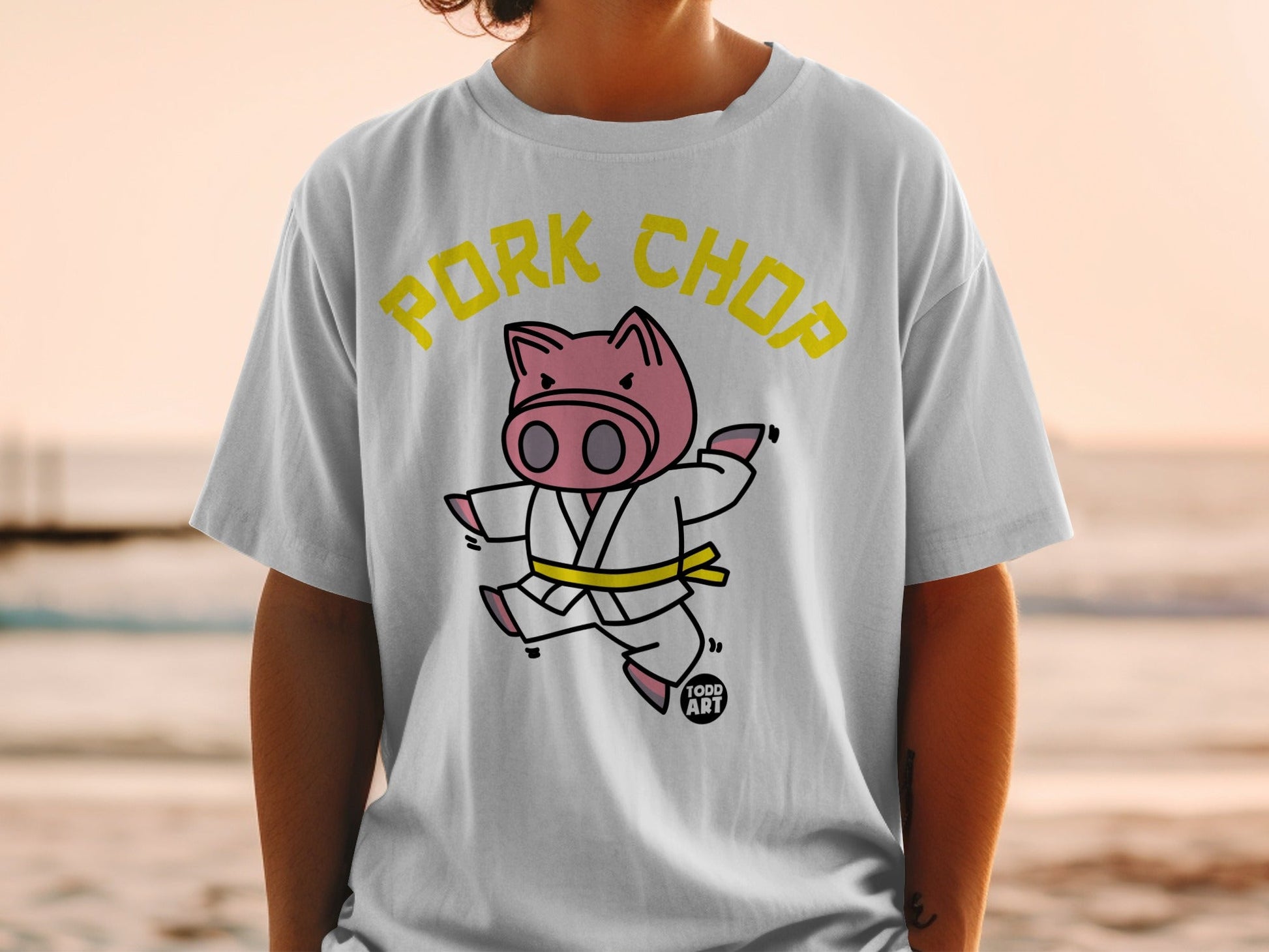 White t-shirt with yellow text "Pork Chop" and cartoon pig in karate gi.