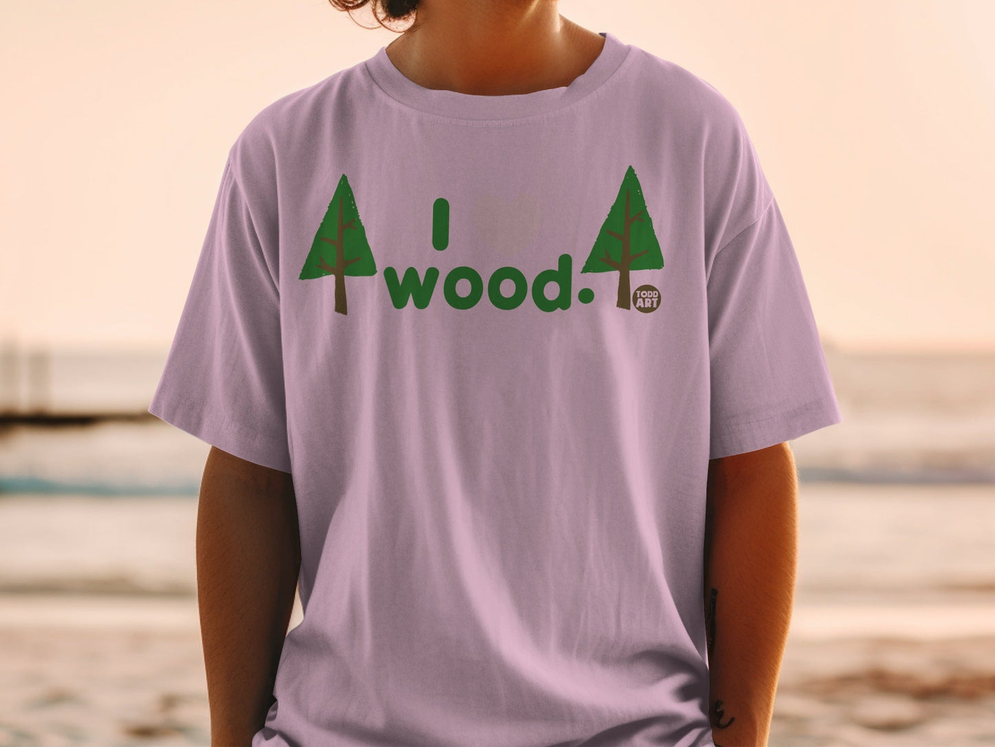Light purple t-shirt with "I wood." text and two evergreen trees.