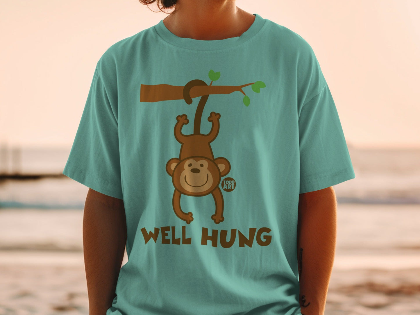 Teal t-shirt with monkey hanging from branch, text "WELL HUNG".