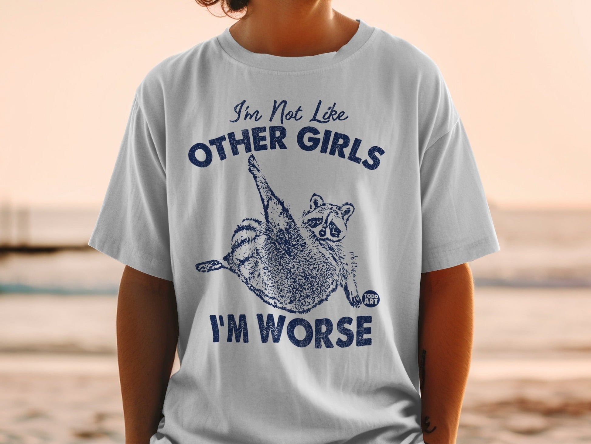 White t-shirt with "I'm Not Like Other Girls I'm Worse" and a raccoon graphic.